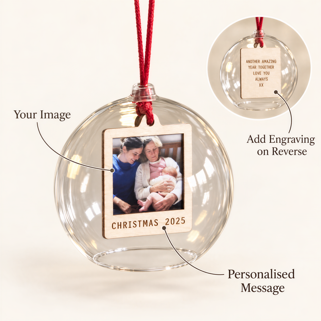 a glass ornament with a wooden frame containing a photograph of a family. The ornament has a red string attached to it, and there are instructions provided for adding engraving on the reverse side.