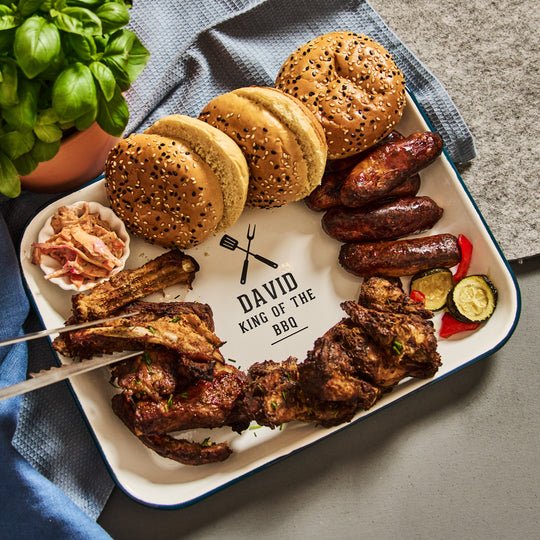 Platter of grilled meats, buns, and vegetables on a tray with &